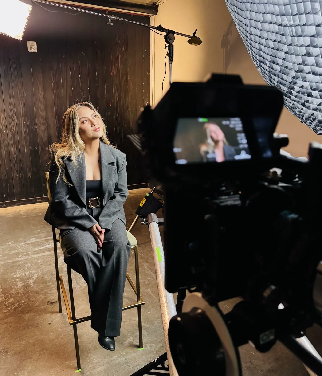 A camera on a tripod and a softbox lighting a seated subject during an interview shoot