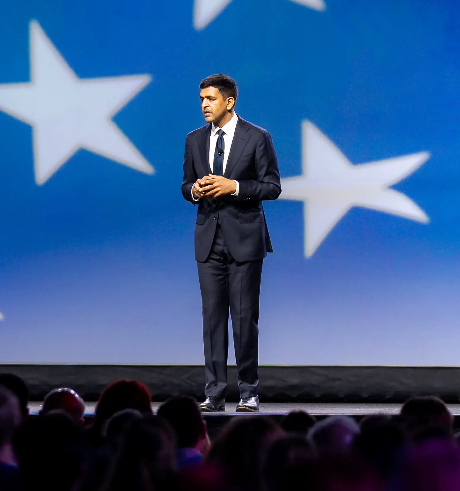 A keynote speaker on stage in front of a large star-patterned screen